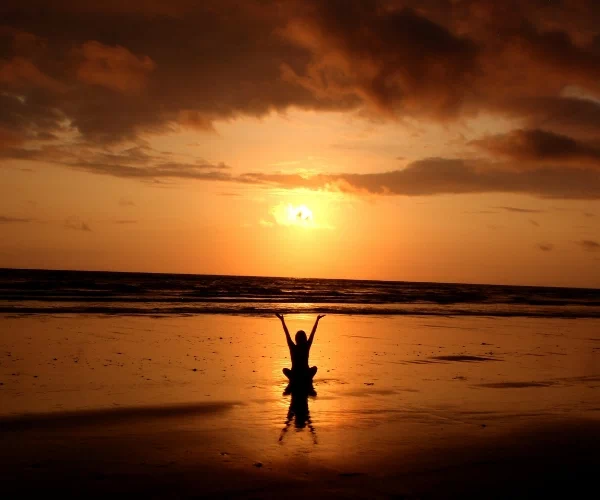kobieta na plaży na tle zachodzącego Słońca